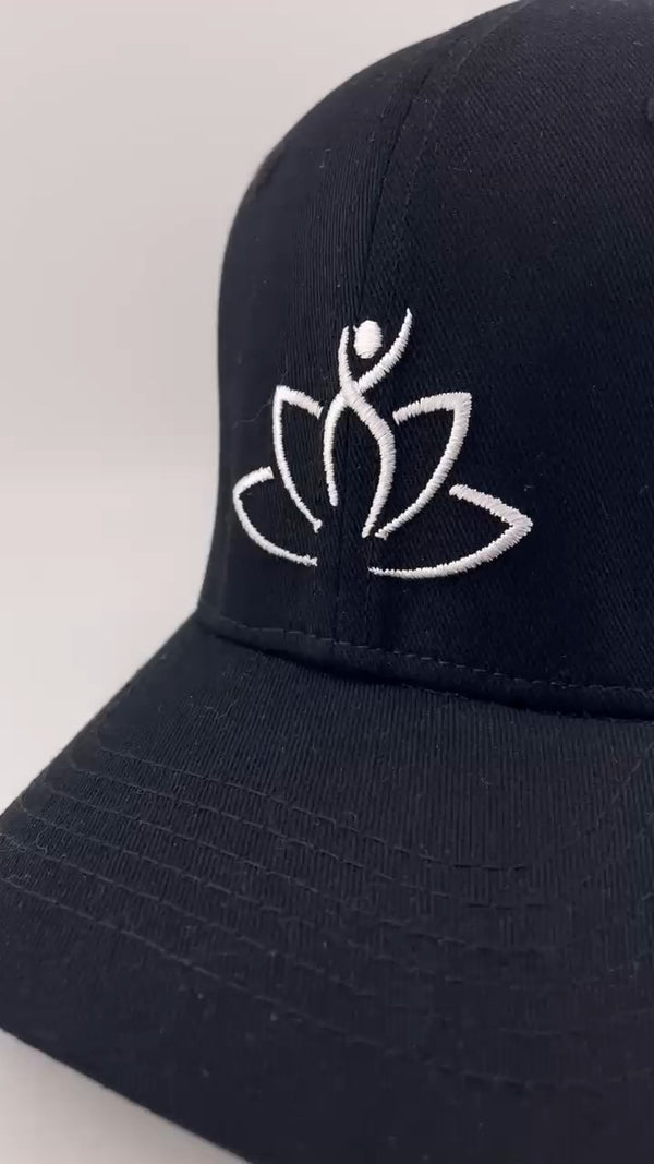 Black cap with white lotus flower and person symbol on a light gray background