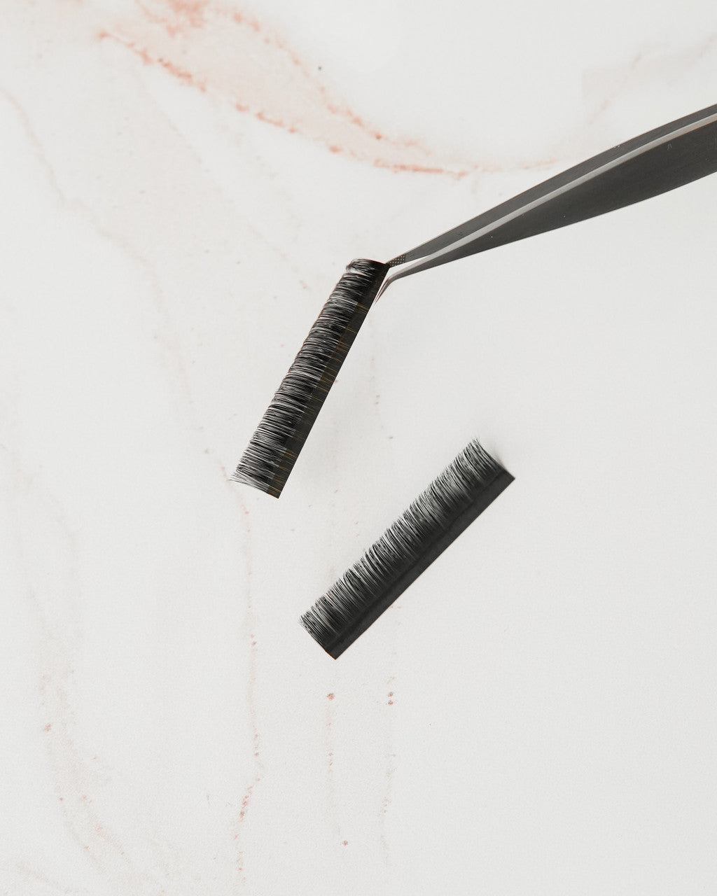 Beutimi FauxMink Lashes 0.02MM tweezers and black lash strips displayed on marble surface