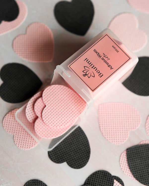 Beutimi Lint Free Adhesive Wipes in pink and black heart shapes displayed on heart-patterned background with product packaging