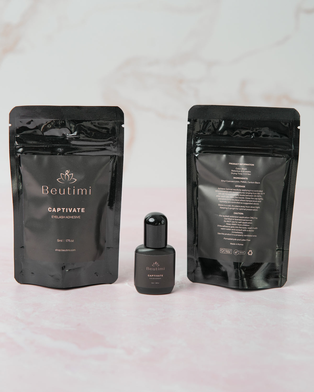 Beutimi Captivate Adhesive displayed as black pouches with bottle on marble background