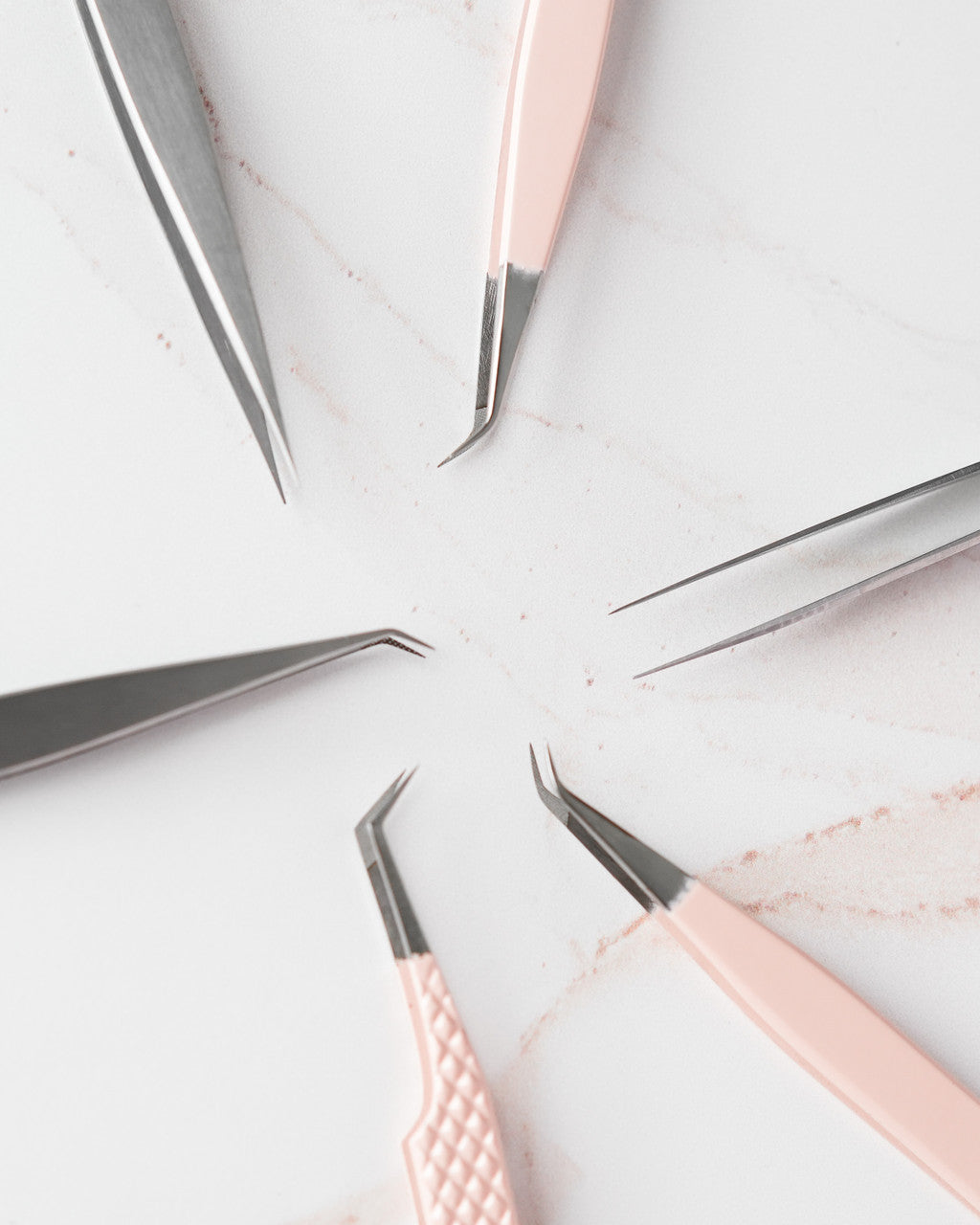 Beutimi Balance Tweezer in pink and stainless steel displayed at angles on white surface with scattered lash materials