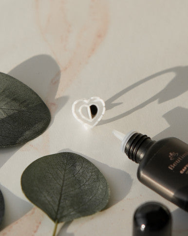 Beutimi Brave Hearts Ring displayed with dried eucalyptus leaves and black adhesive bottle on white surface