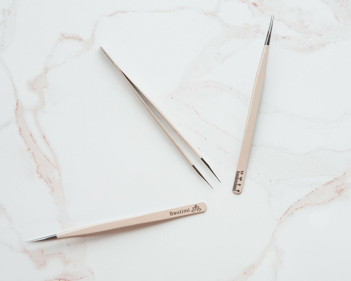 Beutimi On Point Tweezer displayed in beige with fine metal tips and ruler markings on marble surface