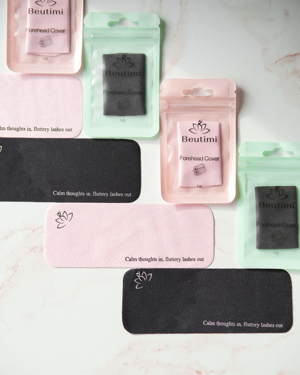Beutimi Forehead Cover in pink and black with lotus logo and affirmation text displayed in packaging and as lash tiles