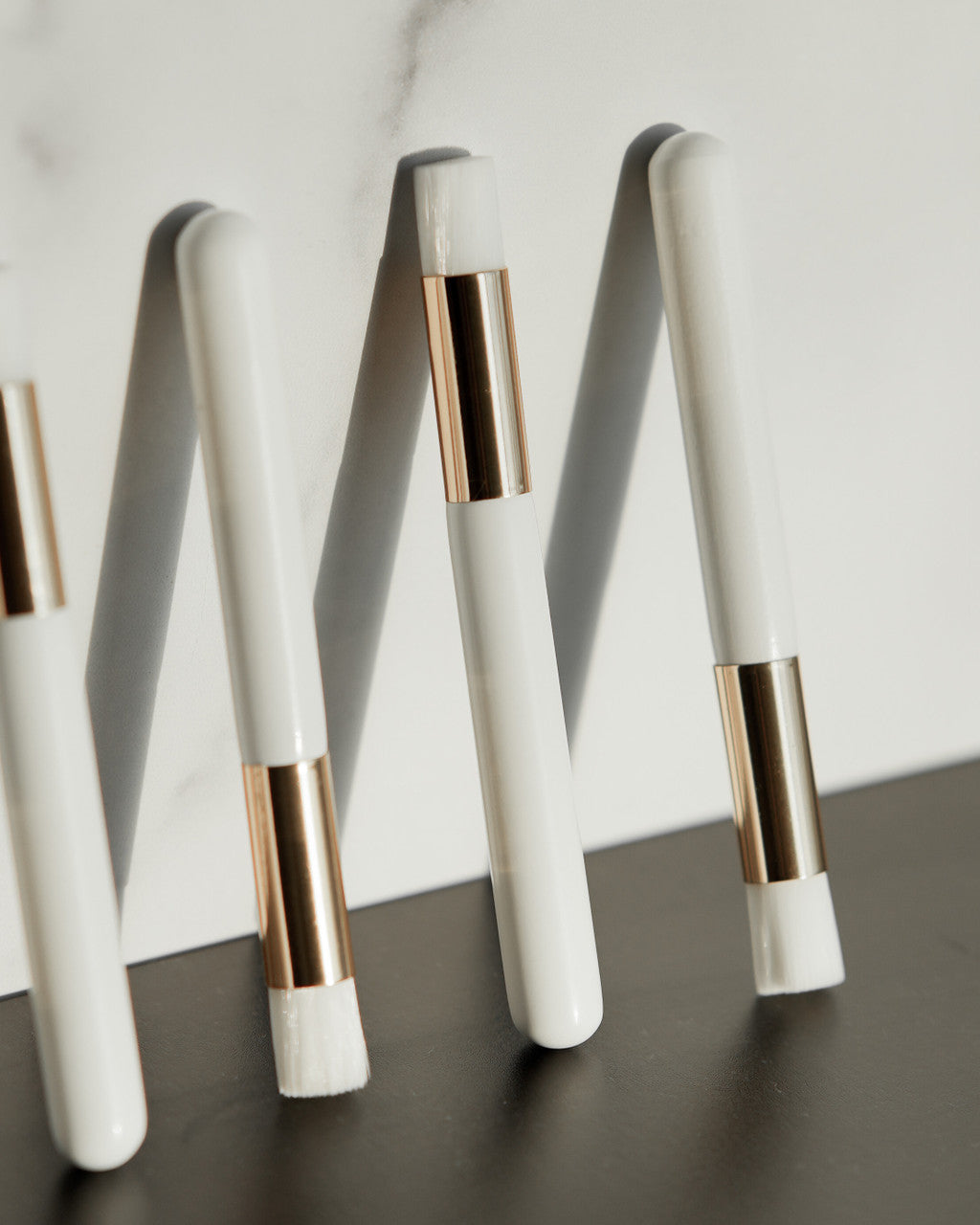 Beutimi Foam Lash Cleanser displayed in white bottles with rose gold bands arranged on a dark surface