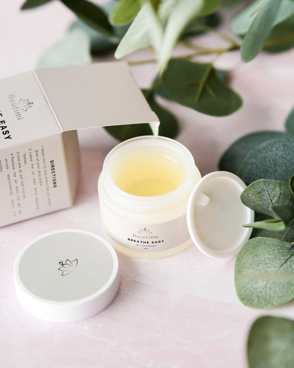 Beutimi Breathe Easy Gel Freshener in white jar with pale yellow gel, displayed open with lid beside eucalyptus leaves and product box