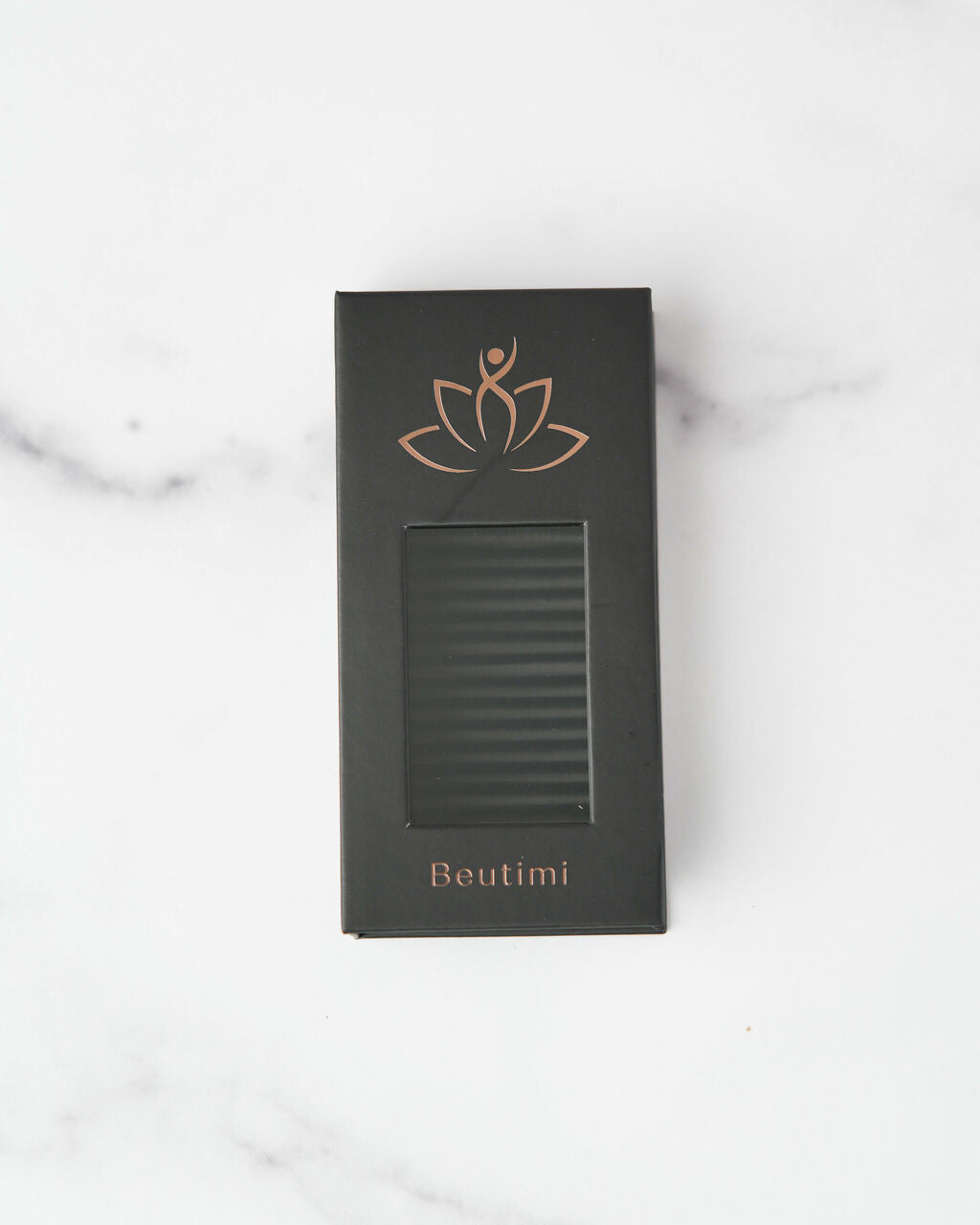 Beutimi FauxMink Lashes 0.03MM black packaging box with copper lotus logo and window display on marble background