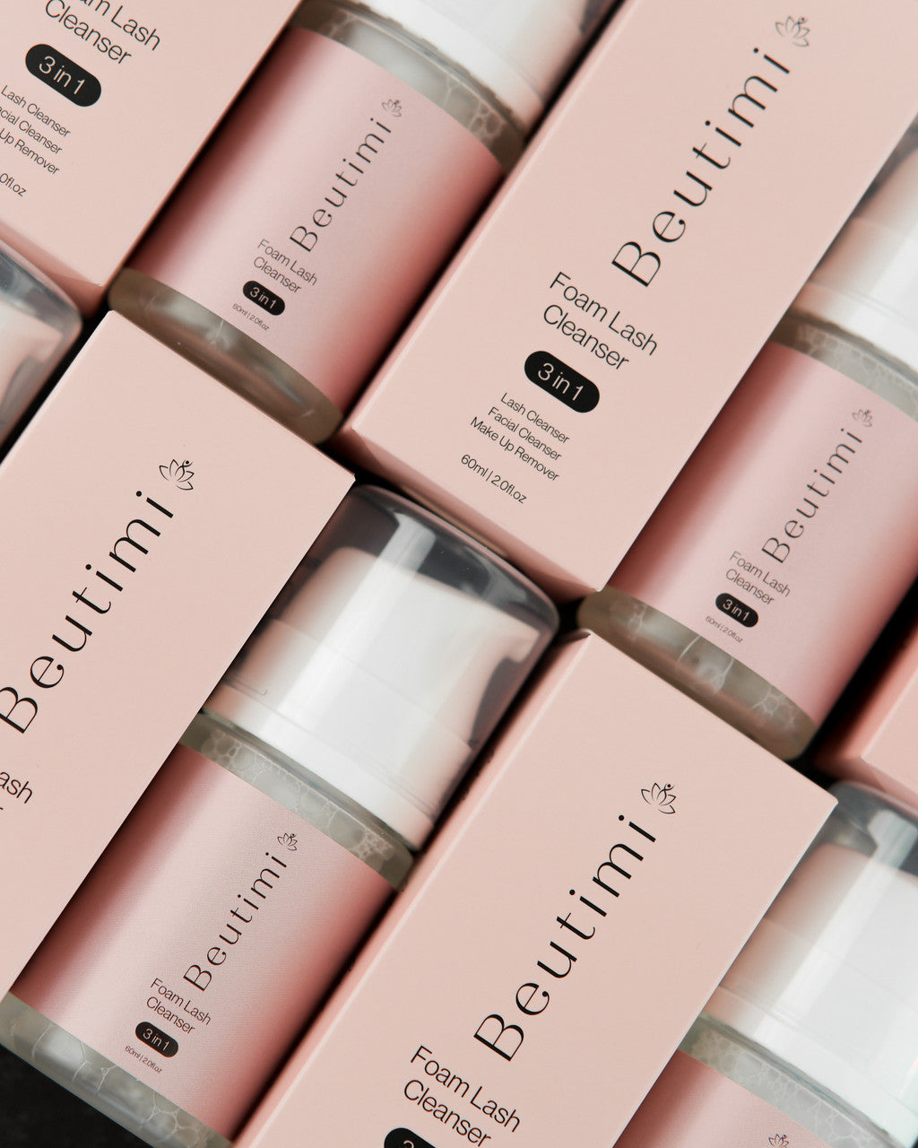 Beutimi Foam Lash Cleanser bottles arranged diagonally on pink background with white caps and product packaging visible