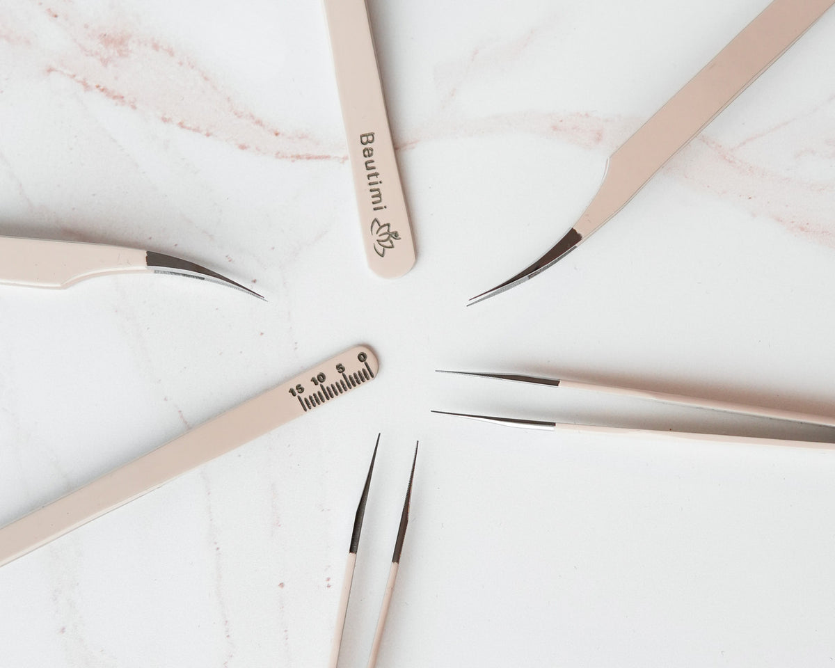 Beutimi Thrive Tweezers arranged in a circle on marble, featuring beige handles with measurement engravings and precision metal tips