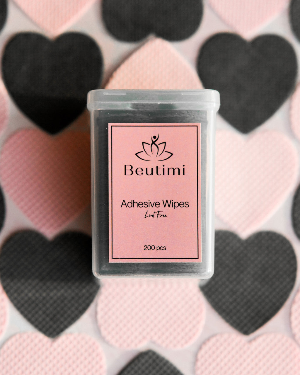 Beutimi Lint Free Adhesive Wipes container with pink label displayed against heart-patterned pink and black background