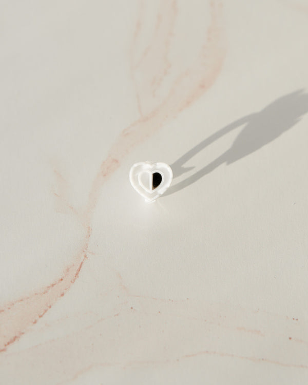 Beutimi Brave Hearts Ring in white heart shape with black center displayed on neutral beige marble surface