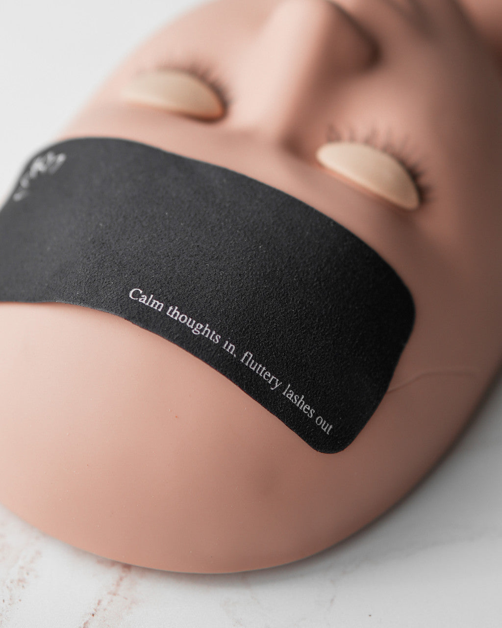 Beutimi Forehead Cover in black and pink displayed from above with motivational text and a manicured hand resting on it