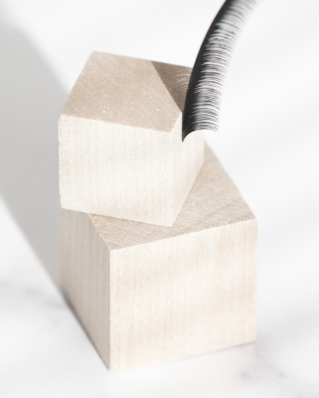Beutimi FauxMink Lashes 0.03MM displayed as stacked cream wooden blocks with a threaded metal tool positioned on top