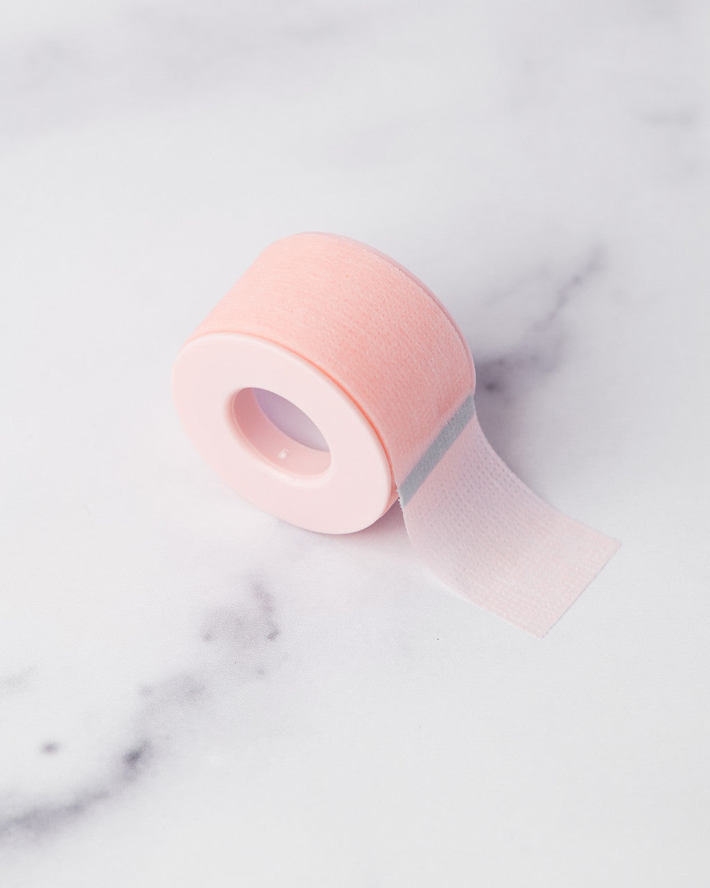 Beutimi Empower Gel Tape in pink displayed partially unrolled on a marble surface showing its gentle adhesive texture
