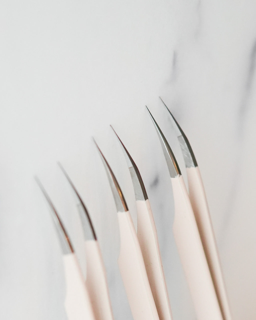 Beutimi Thrive Tweezers displayed in a row showing cream handles with fine metal tips against a white background