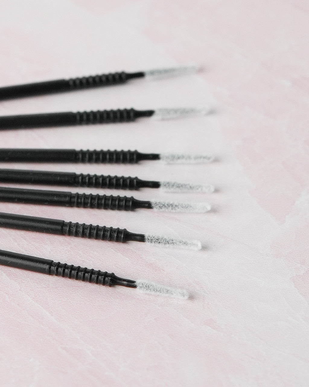 Beutimi Masterpiece Detailers micro brush applicators in black with white bristles arranged in a row on pink surface