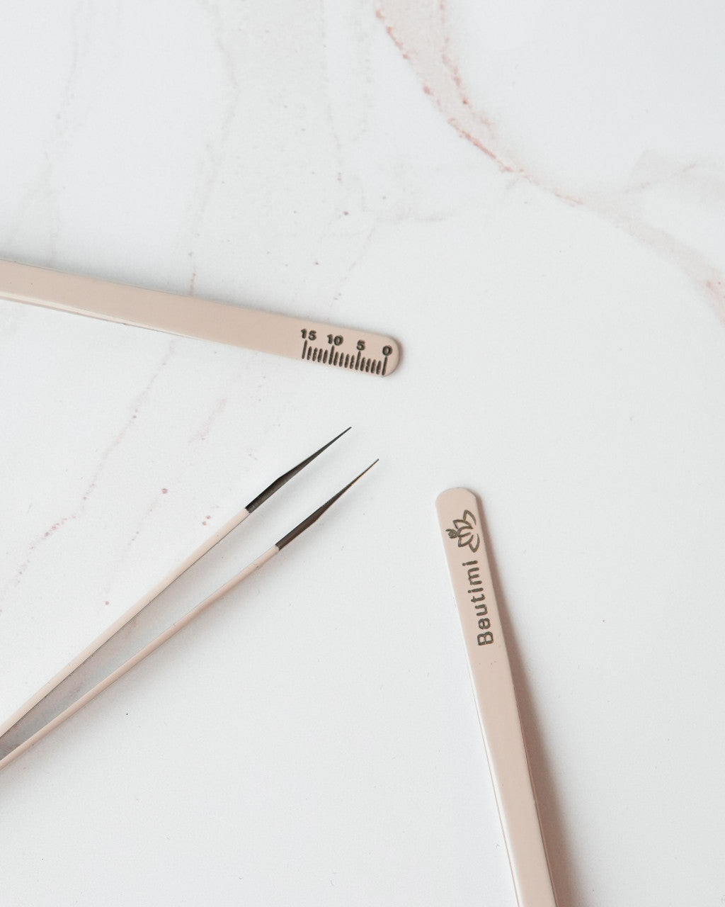 Beutimi On Point Tweezer displayed with fine-tip tweezers and ruler on marble surface showing product details