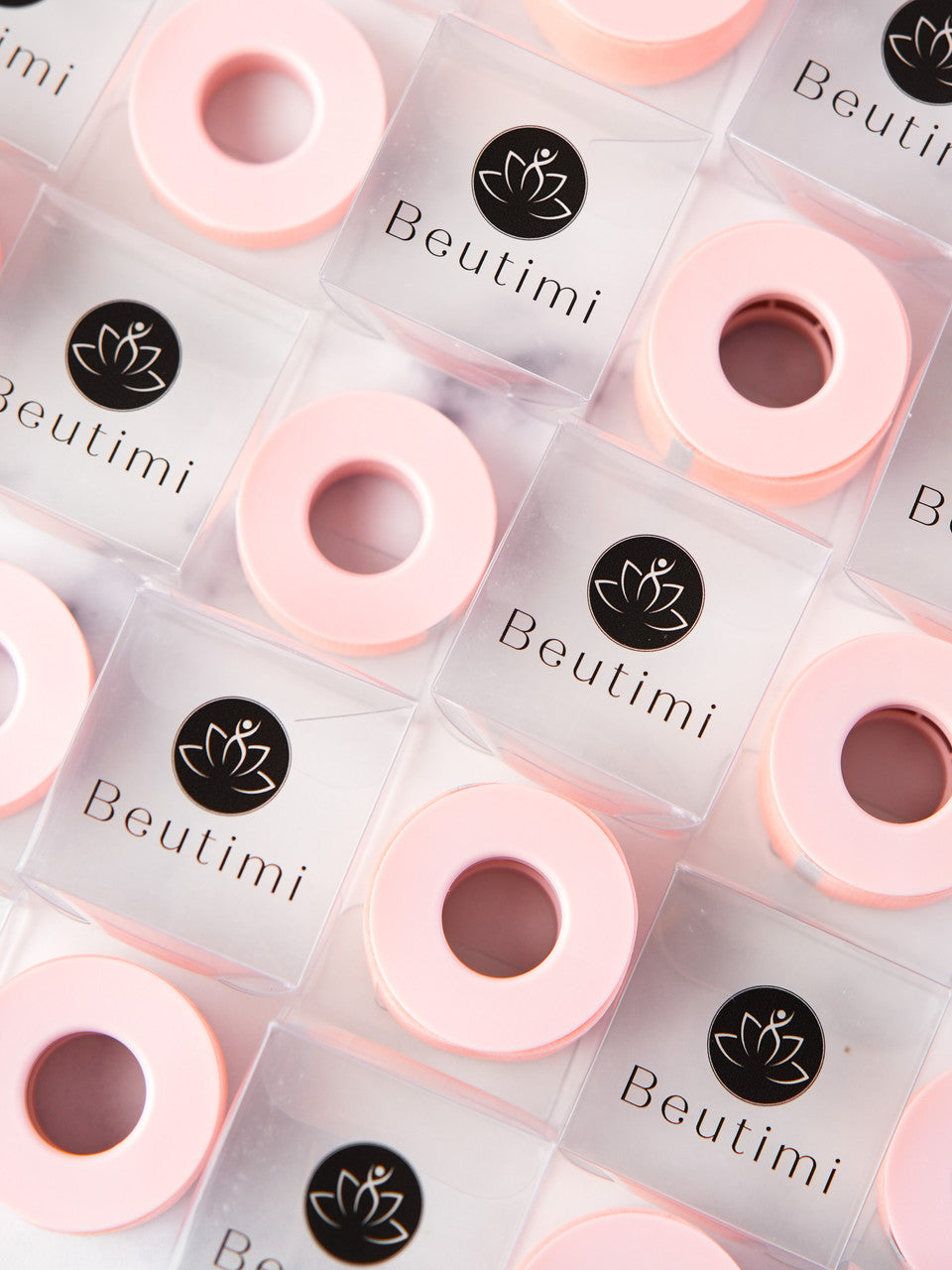 Beutimi Empower Gel Tape in pink rolls with black lotus logo labels arranged in diagonal pattern on white background