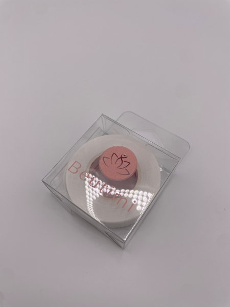 Pink round object with a logo in a clear plastic box on a light gray background