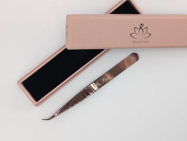 Beutimi Be Bold Tweezer in rose gold with curved fiber tip displayed next to its blush pink packaging with black interior
