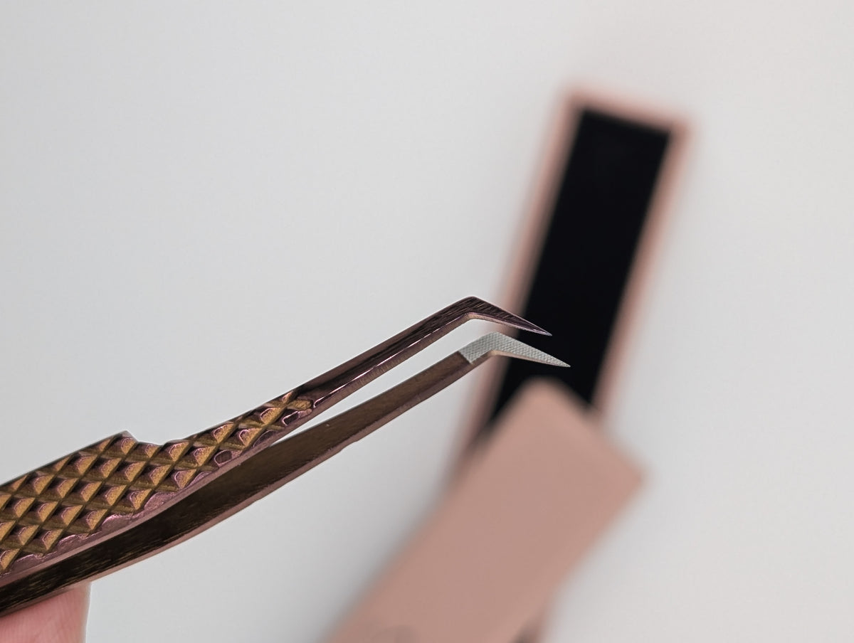 Beutimi Loveself Tweezer with decorative bronze handle and angled fiber tip held in hand against white background