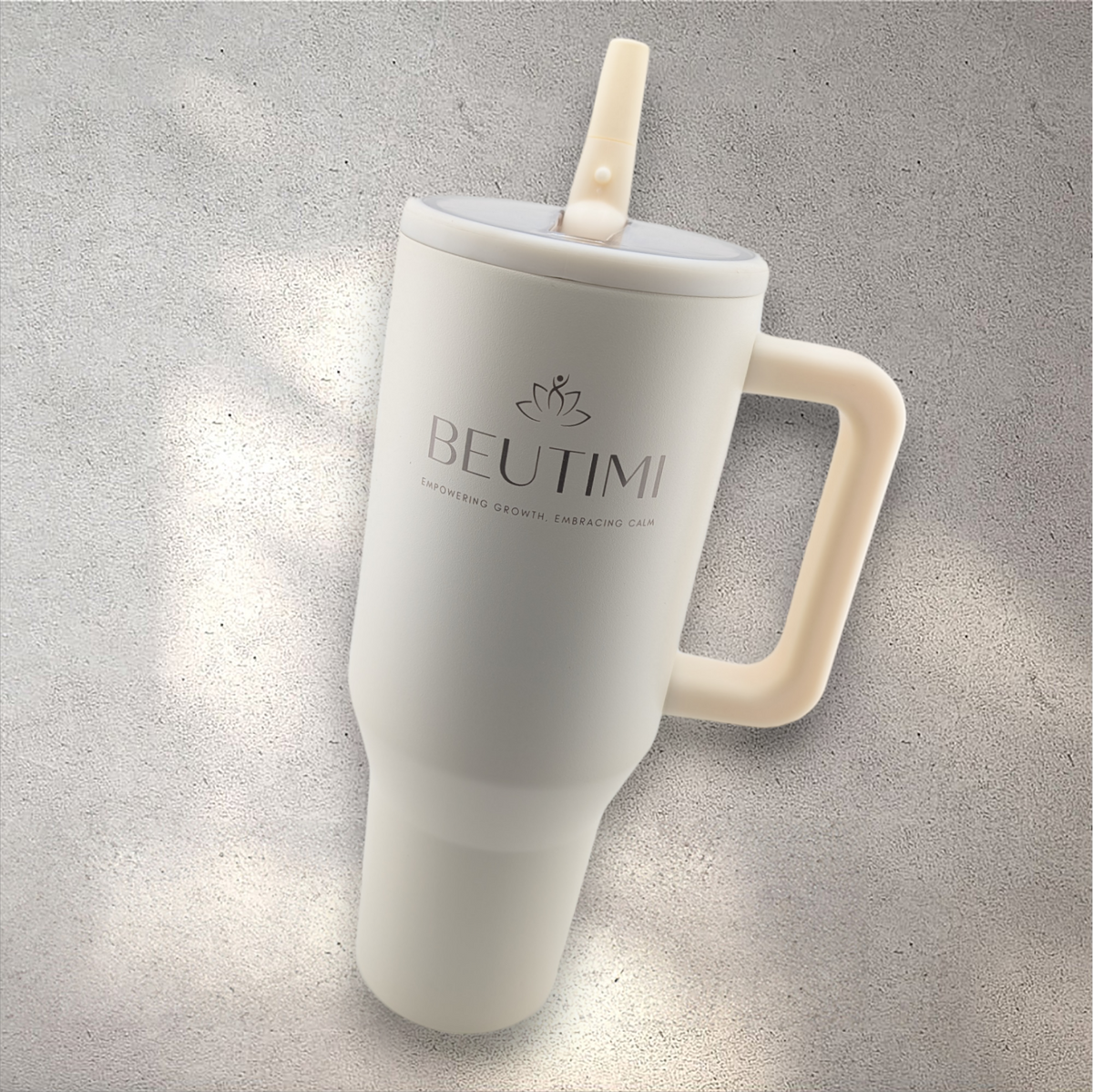 Cream-colored Beutimi Leakproof Hydrojug with lotus logo, flip straw, and handle on concrete background