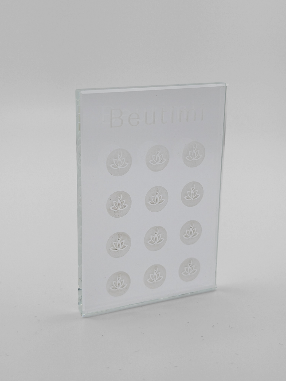 Beutimi Crystal Clear Adhesive Palette displayed as a transparent glass rectangle with twelve lotus flower designs arranged in rows