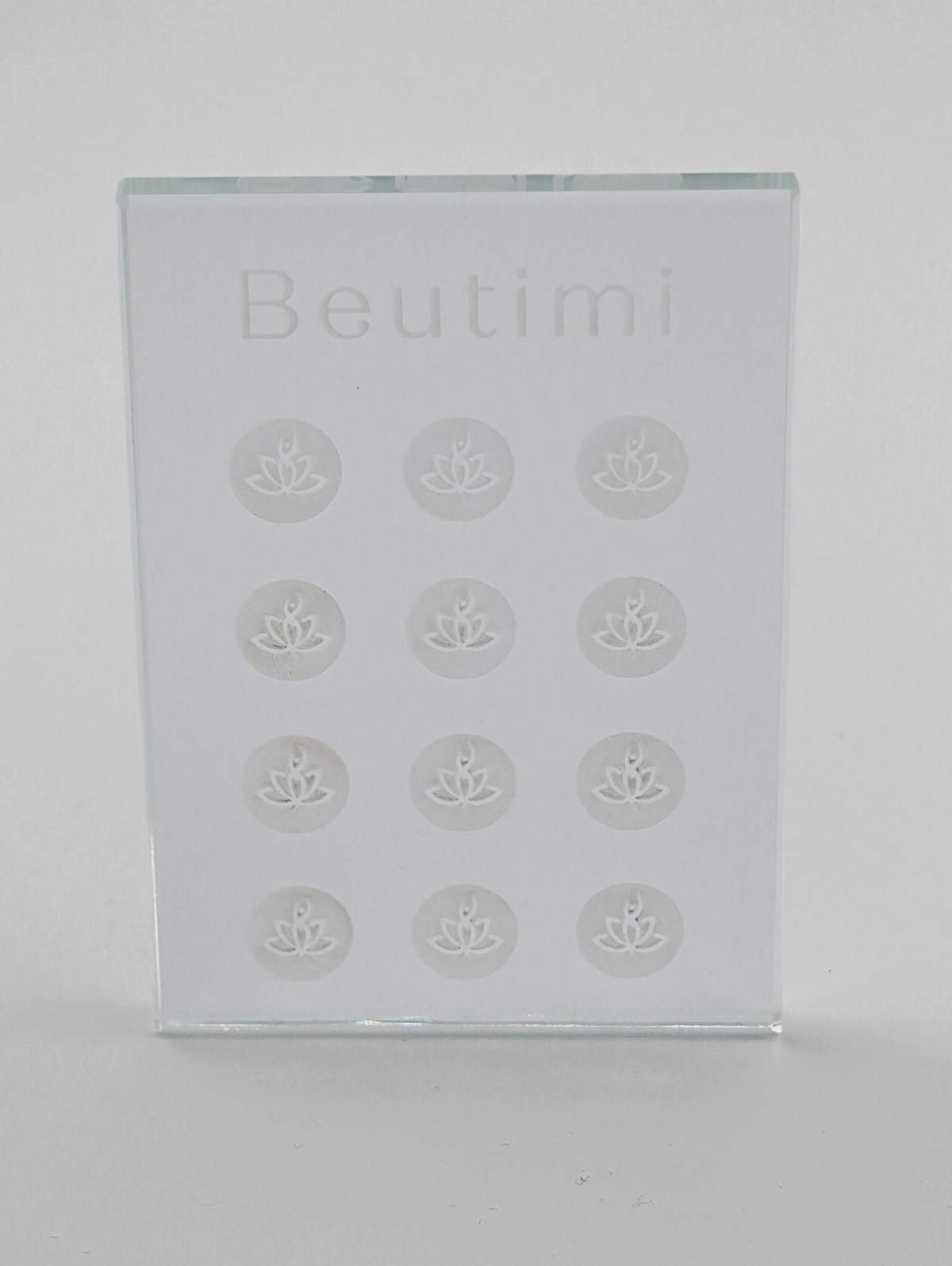 Beutimi Crystal Clear Adhesive Palette displayed in transparent glass with embossed lotus flower wells arranged in a grid pattern