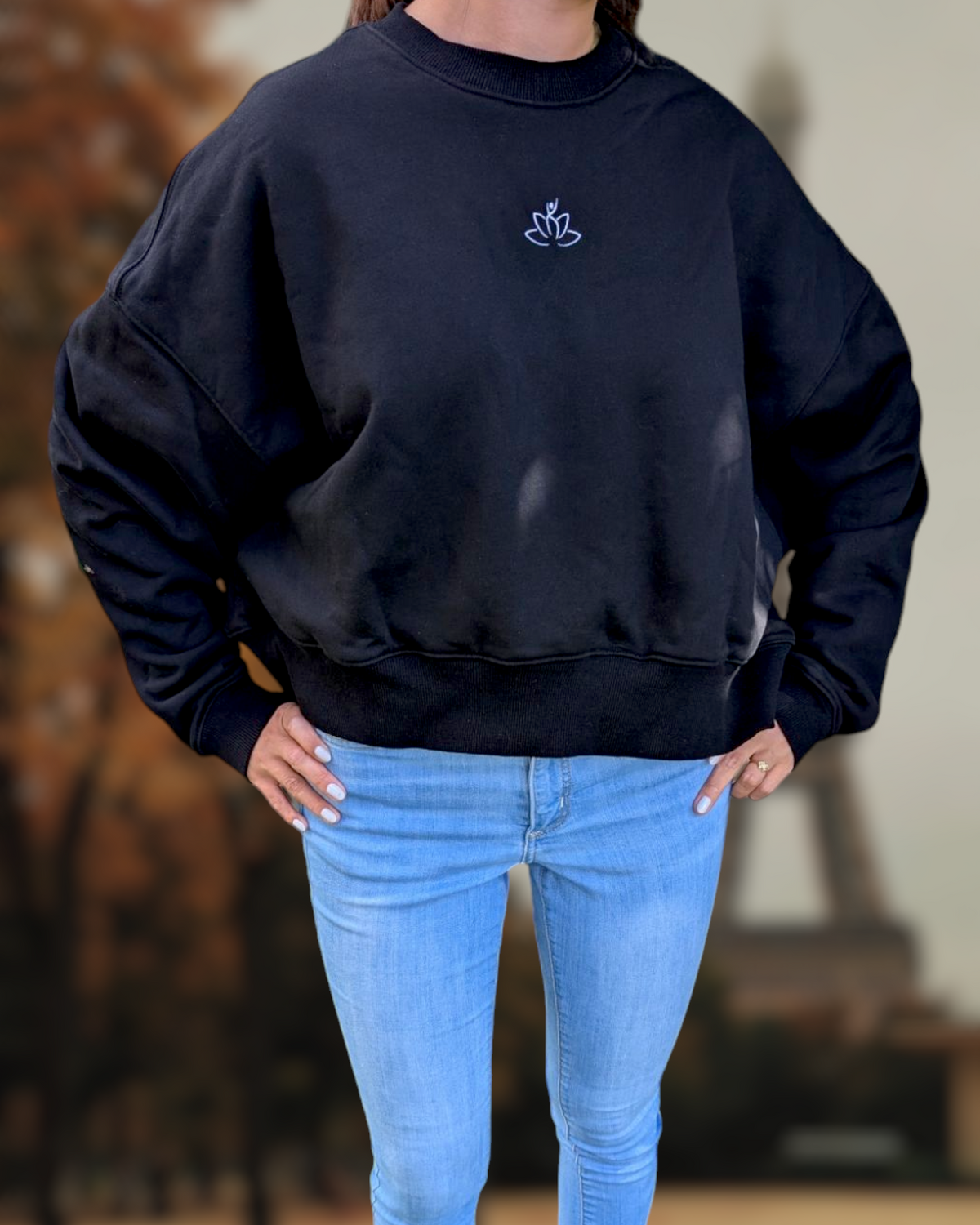 Beutimi Lash Artist Sweater in black with lotus logo, styled with light blue jeans on a model