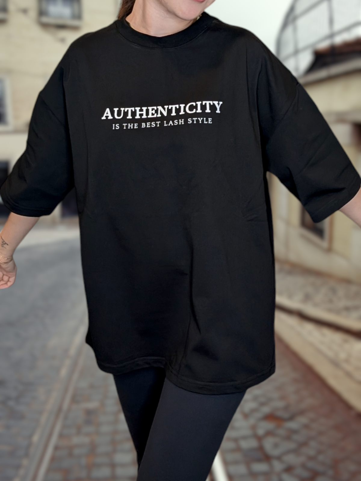 Black Beutimi Authentic T-Shirt with white text reading "Authenticity is the Best Lash Style" worn by model outdoors