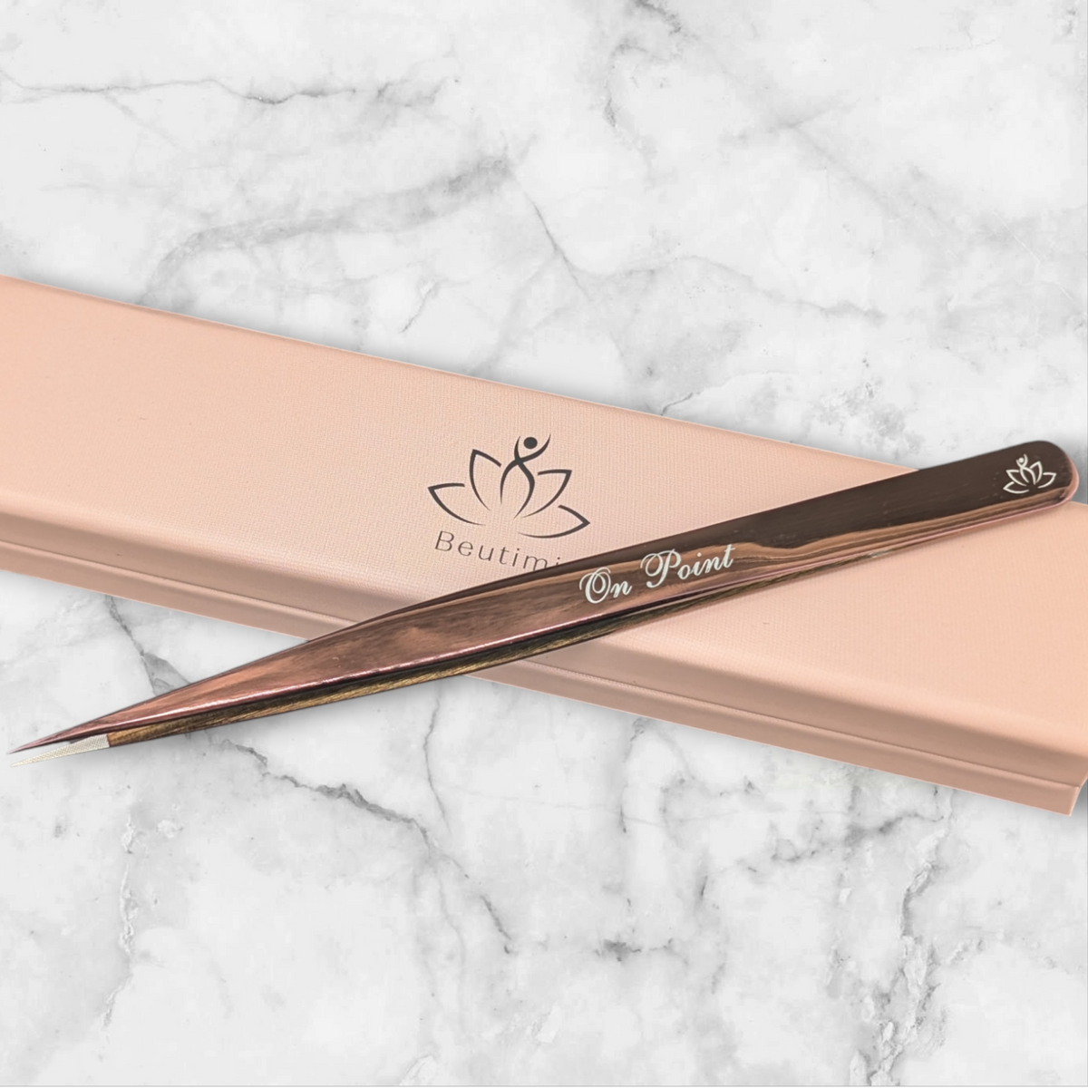 Beutimi On Point Tweezer with dark handle and fine tip displayed on peach packaging against marble background