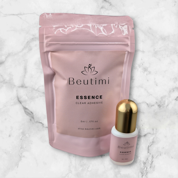 Beutimi Essence Clear Adhesive shown in pink packaging with matching brush applicator bottle on marble background